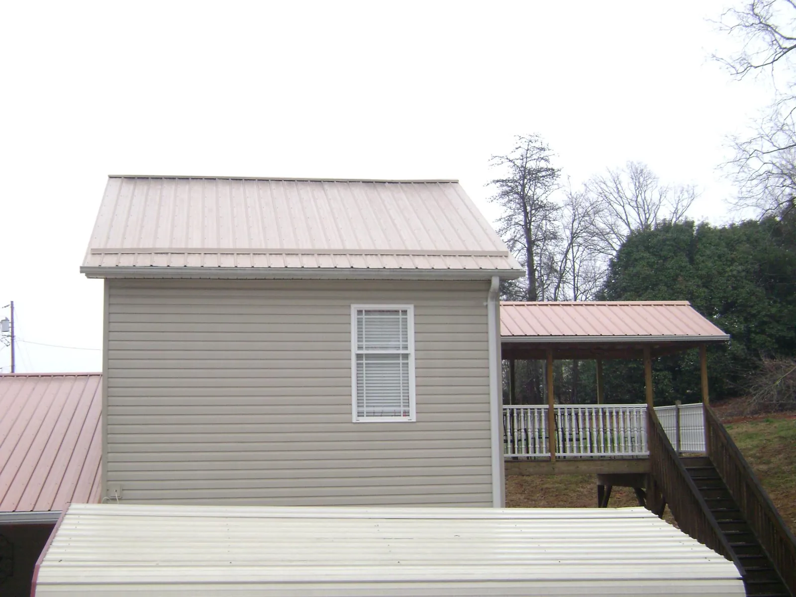 Tan metal roofs on a two story addition and attached porch, from a Roof Replacement job in Lummi Island