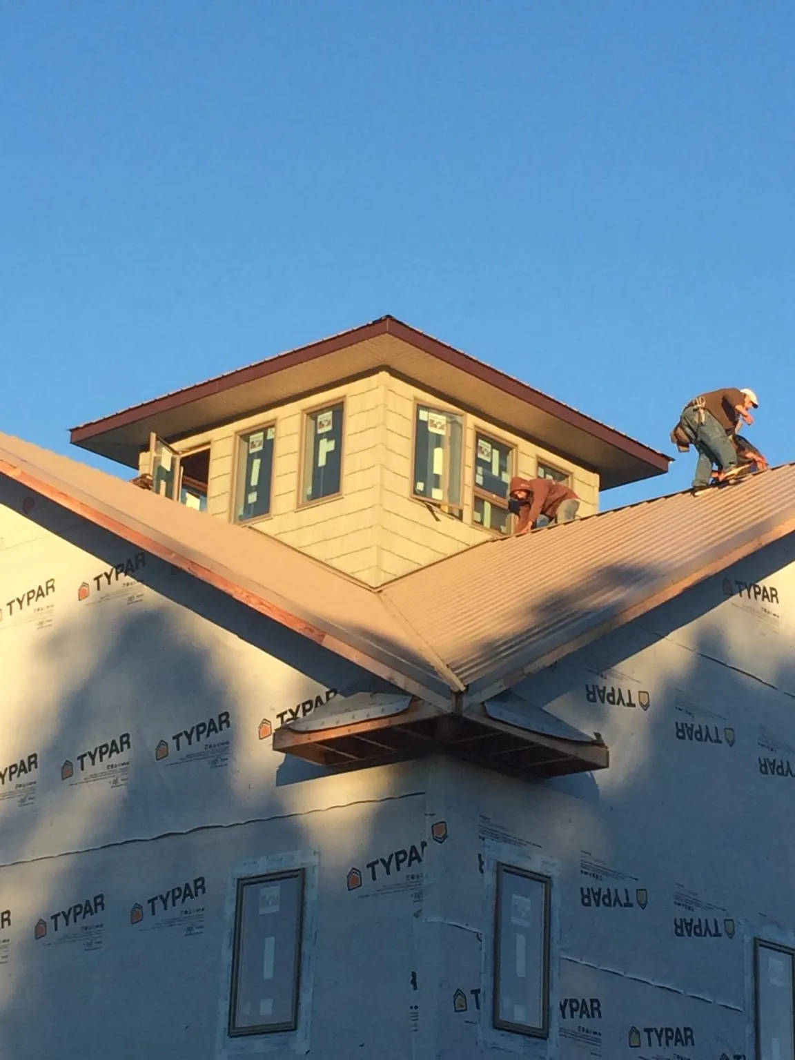 Roofers working around a rooftop cupola on a new metal roof at sunset — Roof Waterproofing in Lummi Island by Roofing Brothers